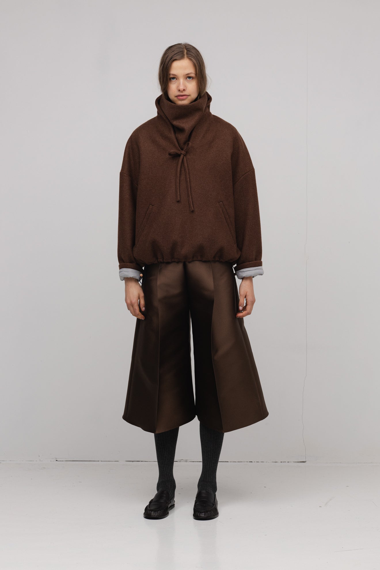 Person wearing a brown outfit with wide-leg pants on a white background