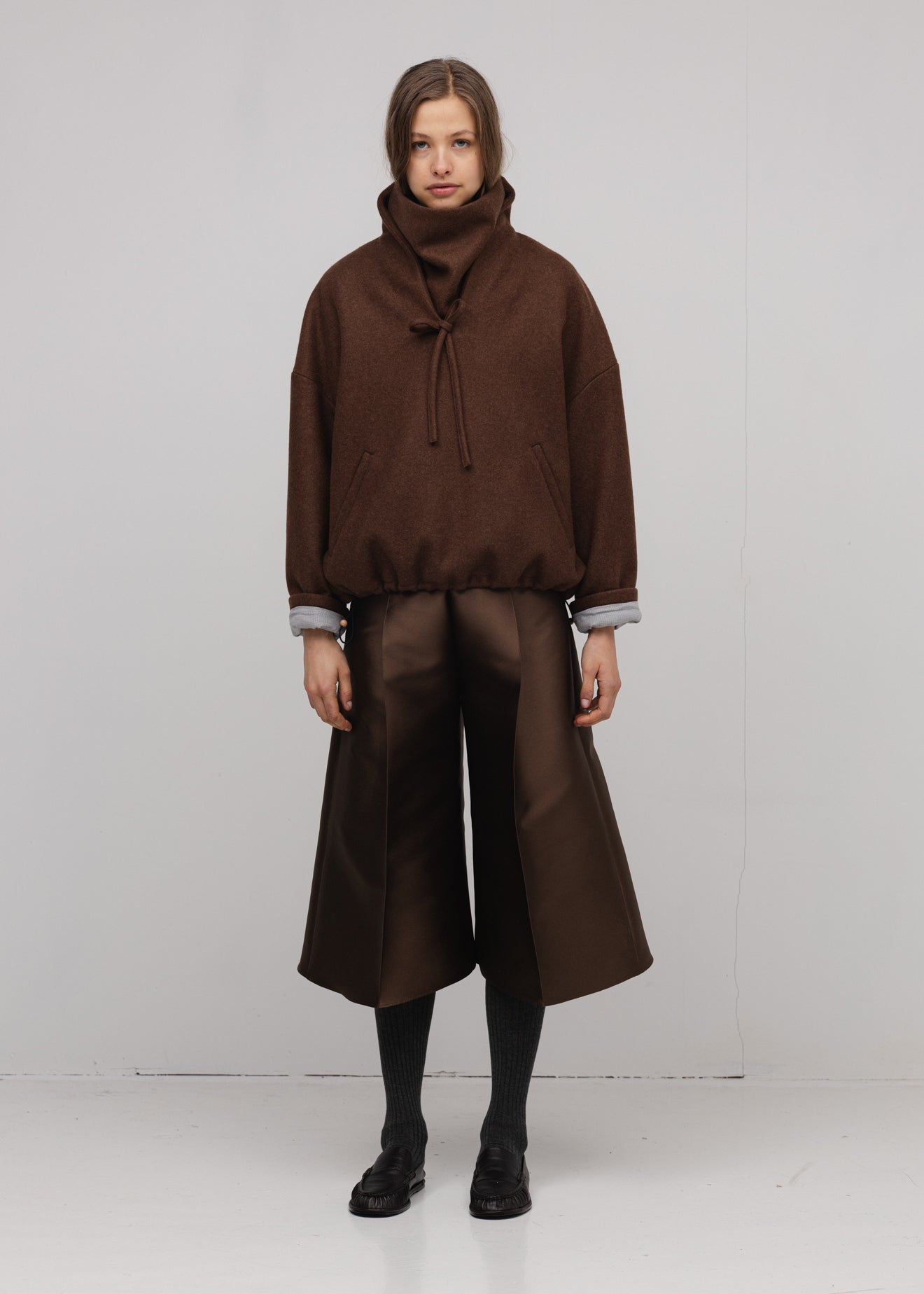 Person wearing a brown outfit with wide-leg pants on a white background