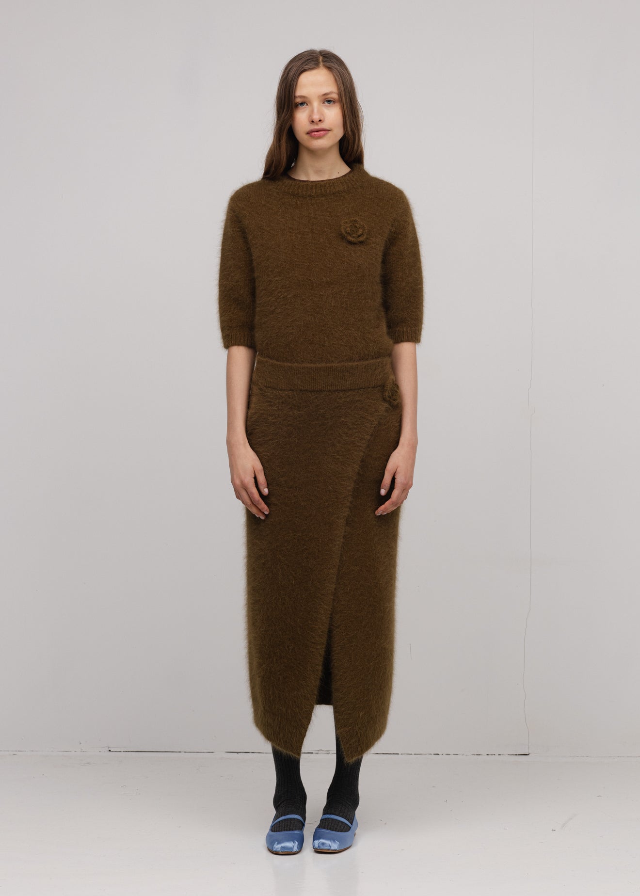 Woman wearing a brown knit outfit with a white background