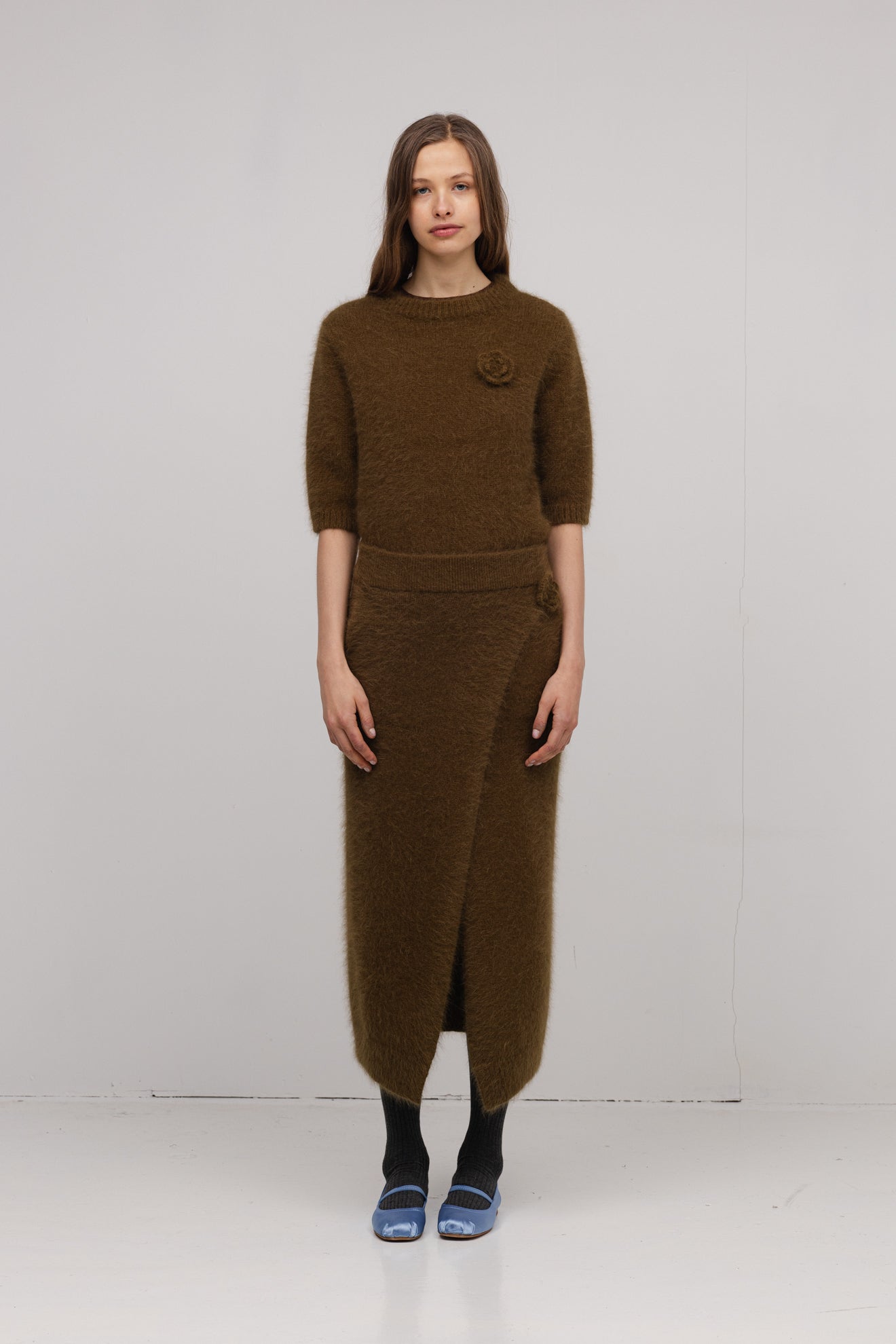 Woman wearing a brown knit outfit with a white background